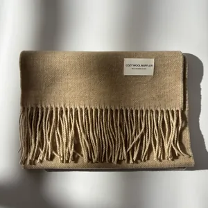 Detailed close-up of premium wool scarf fringe and woven label in camel color