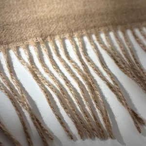 Detail of wool scarf with thick texture and long fringe tassels in camel color