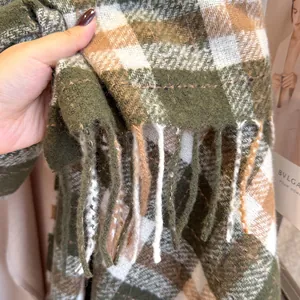 Close-up of thick checkered wool scarf with forest green plaid patterns and long tassels