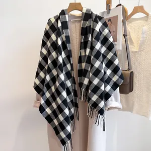 Elegant black and white plaid scarf with tassels styled over a beige winter coat