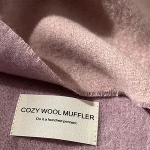 Detailed view of pink wool scarf texture with frayed edges and cozy woven fabric