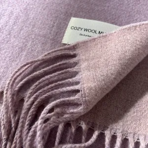 Close-up of grey-purple wool scarf texture showing fine knit weave and long fringe trim