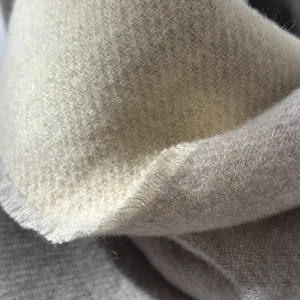 Macro detail of high-quality wool scarf showing twill weave and soft fringed edges