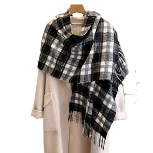 Classic black and white plaid wool scarf with fringe draped over a camel coat
