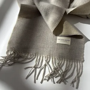 Detail of light grey wool scarf showing fine texture, fringe edges and woven series label