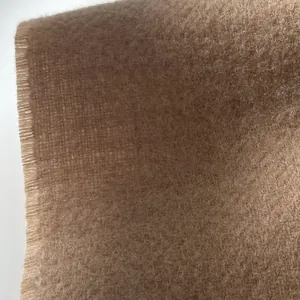 Close-up detail of soft wool fabric texture with natural fringe edge in camel brown