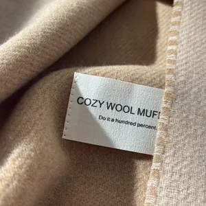 Close-up of camel wool scarf showing soft texture and premium stitched brand label