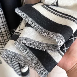 Detail view of woven black and white geometric pattern scarf with soft gray fringe trim