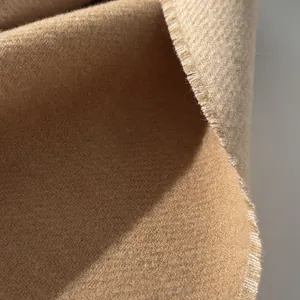 Macro detail of camel wool scarf showing thick soft texture and neat fringed edges