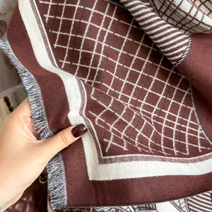 Detail of soft thick scarf featuring dark brown jacquard pattern and fringe edges