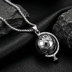 Macro detail of rotating stainless steel globe pendant with box chain on dark stones