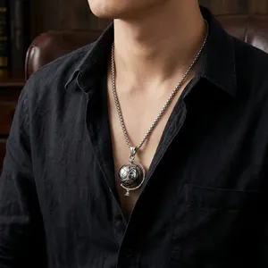 Close-up of men's spinning globe pendant in silver finish on a vintage square pearl chain