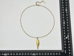 Détail du pendentif carpe koi dorée avec écailles ciselées et règle de mesure à côté