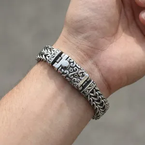 Macro detail of men's titanium steel dragon chain with embossed floral clasp