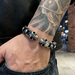 Punk style leather bracelet featuring twin skull heads and vintage silver finish on wrist