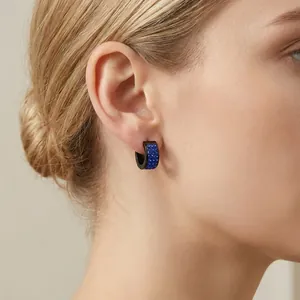 Minimalist black and blue crystal paved hoop earrings worn on female ear for daily style