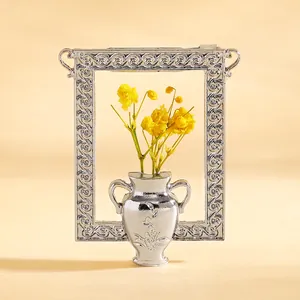 Detailaufnahme Bilderrahmen mit silberner Vase und leuchtend gelben Trockenblumen