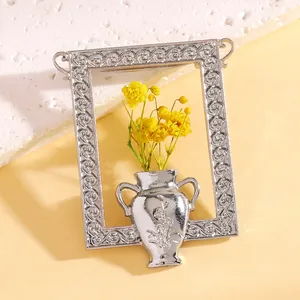Detail einer silbernen Vintage-Rahmenbrosche mit strukturierter Vase und gelben Trockenblumen