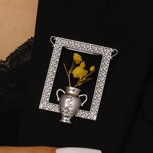 Nahaufnahme der Vintage Rahmenbrosche mit gelben Trockenblumen auf einem Sakko