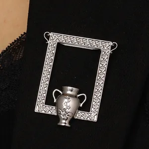 Detailaufnahme einer Vintage-Silberbrosche mit Vasen-Motiv auf schwarzer Spitze und Stoff