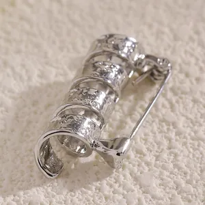 Detailaufnahme der silbernen Spiralbrosche mit strukturierter Hammerschlag-Optik