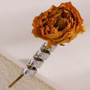Nahaufnahme silberner Ringe mit Lava-Struktur, gestapelt auf einem Rosenstiel