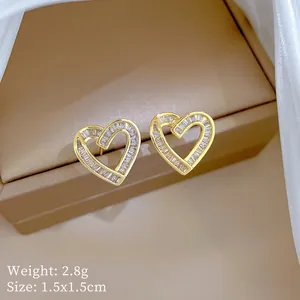 Close-up of golden heart earrings with zircon inlay, 1.5x1.5cm detail view