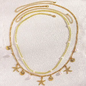 Detailansicht der mehrlagigen Goldkette mit Seestern-, Muschel- und Perlenanhängern.