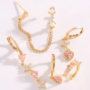 Dettaglio di orecchini dorati con pietre rosa a cuore e goccia con perle