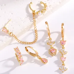 Dettaglio degli orecchini dorati con zirconi rosa e perle su pietre bianche