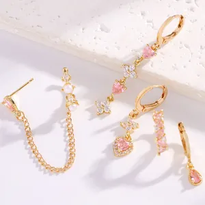 Dettaglio di set orecchini in zircone rosa con motivi a cuore e luna in oro