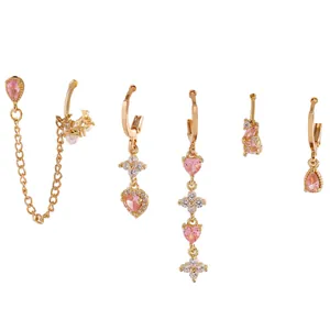 Dettaglio di orecchini a cerchio dorati con ciondoli a cuore rosa e pietre di zircone