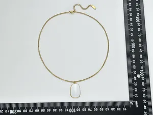 Dettaglio della collana dorata con pendente bianco da 25 mm e scala di misura