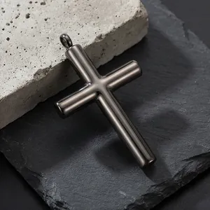 Dettaglio del ciondolo a croce in metallo scuro su pietra con finitura metallica