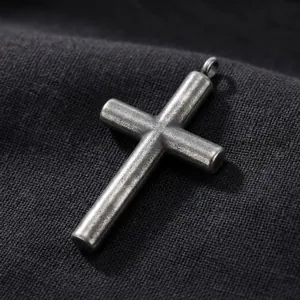 Dettaglio macro di un ciondolo a croce in argento vintage con finitura in metallo spazzolato