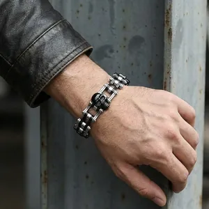 Close-up of men's stainless steel bicycle chain bracelet with black skull detail
