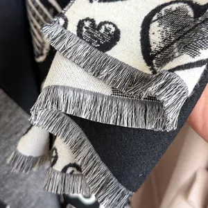 Close-up of black and white heart jacquard knit scarf featuring soft fringe detail
