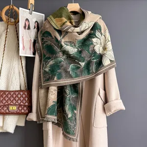 Elegante sciarpa floreale magnolia verde scuro e beige con frange su un cappotto di lana
