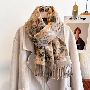 Detail of paisley pattern and soft fringes on a beige cashmere-feel winter scarf