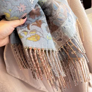 Detail of gray-blue paisley cashmere scarf with colorful tassels and soft floral patterns