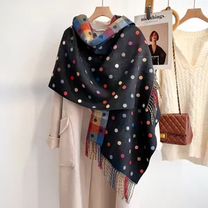 Colorful polka dot black cashmere scarf with fringe tassels on a beige coat