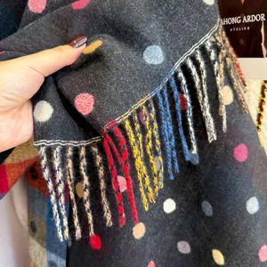 Close-up of soft dark grey scarf texture with colorful dots and fringe tassels