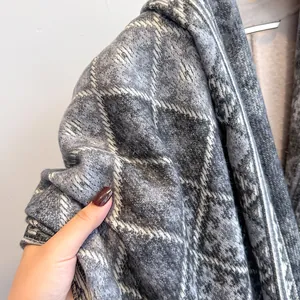 Dettaglio ravvicinato della morbida trama della sciarpa a quadri grigia in finto cashmere