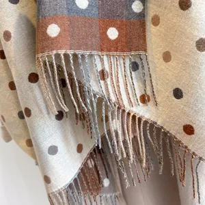 Close-up of soft cashmere-feel scarf texture featuring color blocks and polka dots