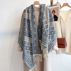 Dettaglio di uno scialle vintage a quadri con motivi a maglia e lunghe frange su gruccia
