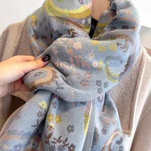 Detailed texture of blue paisley cashmere shawl with soft fringe on wool coat background