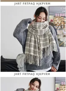 Detail of soft beige plaid scarf with black stripes and long tassels on grey sweater