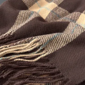 Macro shot of thick plaid scarf featuring soft cashmere-like texture and tassel fringe edges
