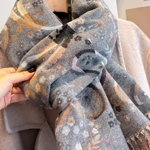 Close-up of grey paisley patterned scarf with fringe detail and soft cashmere-like texture