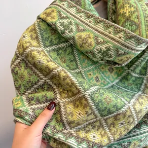 Dettaglio di una sciarpa morbida con motivi geometrici a rombi verde giallo e marrone